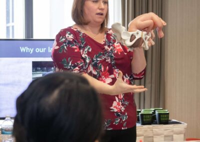 Hollie Hauptly, a childbirth educator in Lehi, UT, teaching a birth class using a model pelvis and baby doll to demonstrate the baby moving through the pelvis during labor.